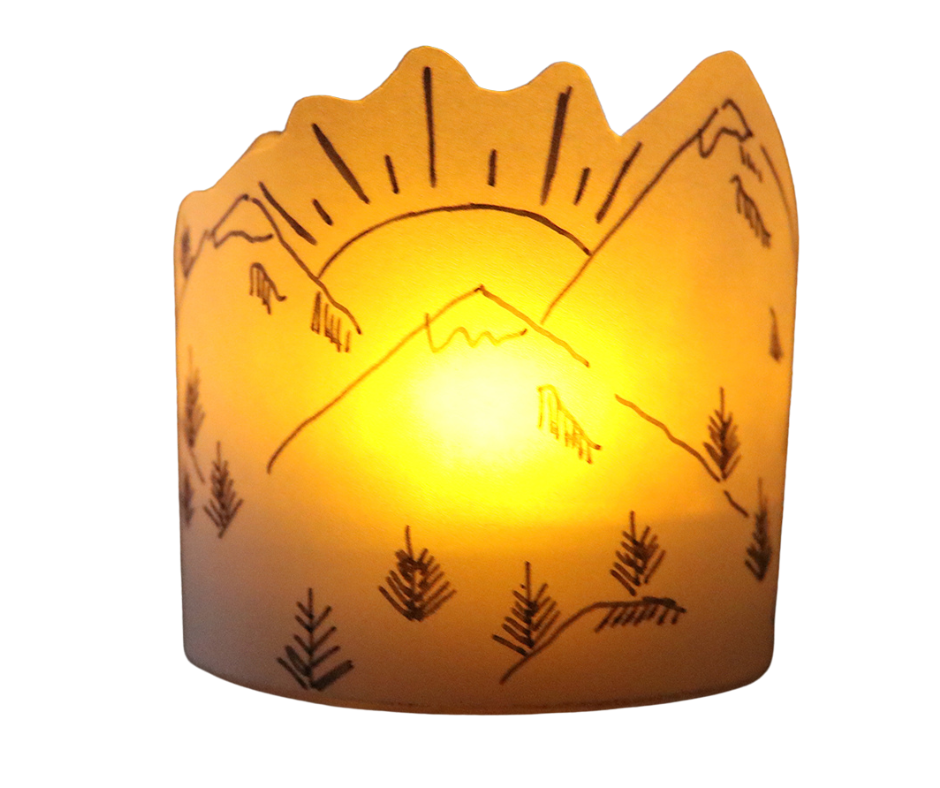 A white paper lantern with a mountain scene glowing from a tea light.